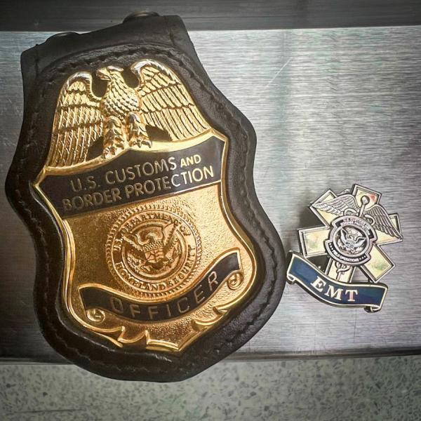 Photo of a CBP officer badge and EMT pin. CBP EMTs helped to save an unresponsive woman at Washington Dulles International Airport on February 6, 2022.