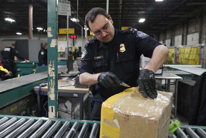 A CBP Officer inspects a package. 