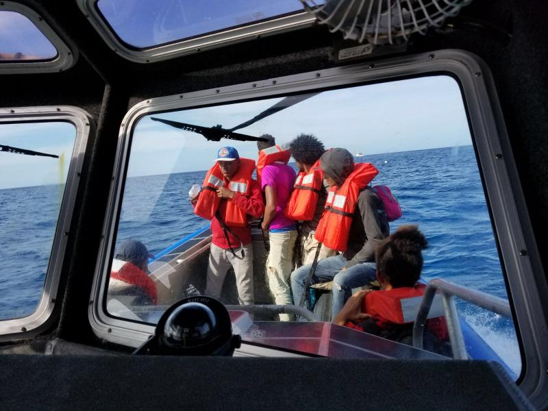 A group of migrants is transported to a USCG cutter for processing.  