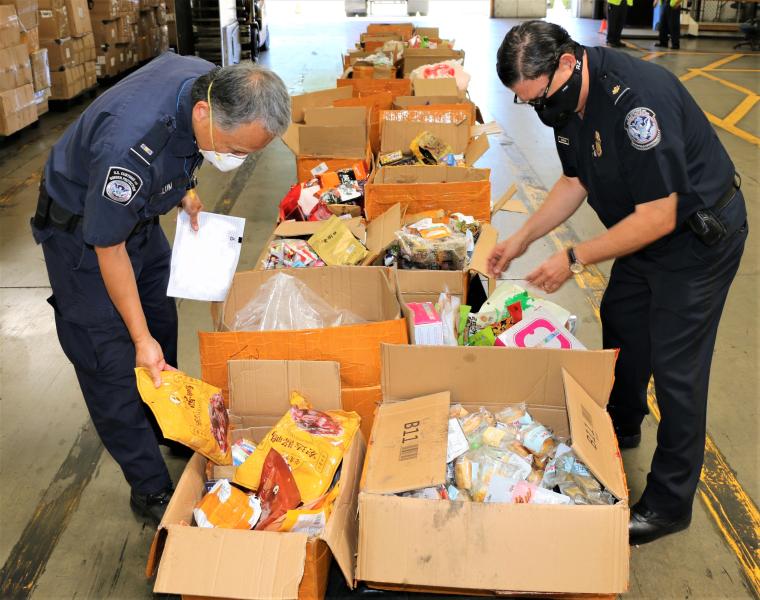 Two Agriculture Specialists Inspect a Food Contraband Shipment
