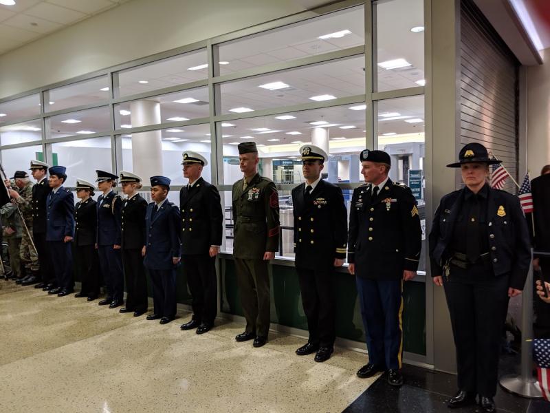CBP Officer Karol Strey (R) and military personnel stand at attention during an Honor Flight ceremony welcoming home veterans from World War II.
