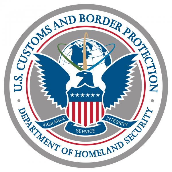 Image of the CBP seal. A blue eagle with wings spread gazes to the left. The eagle holds an American flag-themed shield in front of its torso. Under the flag, a banner bears the CBP core values: vigilance, service, integrity. In the background, blue, green, and yellow lines traverse a globe centered on the north Atlantic. The globe and eagle are surrounded by red and grey circles, between which are written "U.S. Customs and Border Protection - Department of Homeland Security."