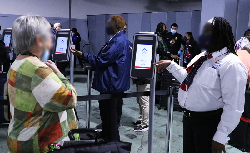 passenger approaches the biometric facial comparison machine while Carnival Cruise Line employee stands nearby