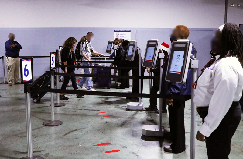 Carnival Cruise Line personnel man lanes of new facial biometric debarkation hardware while cruise passengers debarking walk up to them to have their faces scanned